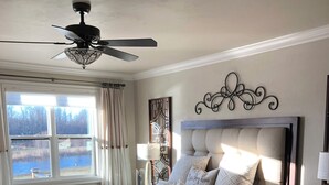 A bedroom with a large bed, a ceiling fan, a window with a view of a body of water, and a decorative wall piece. - Plan for EAA ! Executive ranch, only 13 miles away  (Neenah)