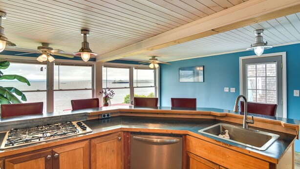 A kitchen with a stainless steel stove, dishwasher, and sink. There are wooden cabinets and a window with a view of the water. - Massachusetts Vacation Rental: 5 Mi to Fall River (Somerset)