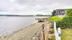 A coastal view with a pebbled beach, a white fence, and a modern building with balconies. - Massachusetts Vacation Rental: 5 Mi to Fall River (Somerset)