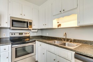 Enjoy cooking in this well-equipped kitchen with a double sink, shelf, and modern appliances.
