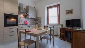 A modern kitchen with a dining area, featuring a built-in oven, a television, and a window with a view. - La Casetta di Dado by Wonderful Italy (Turin)