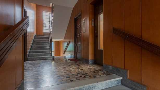 A staircase with a marble floor leading to an elevator, surrounded by wooden paneling. - La Casetta di Dado by Wonderful Italy (Turin)