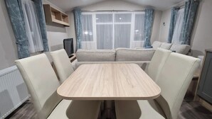 Un comedor con una mesa rectangular rodeada por cuatro sillas, un sofá y un televisor.
