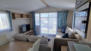 Una sala de estar moderna con un conjunto de sofás, un televisor y un comedor.