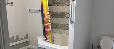 A bathroom with a shower, toilet, and a small step stool.
