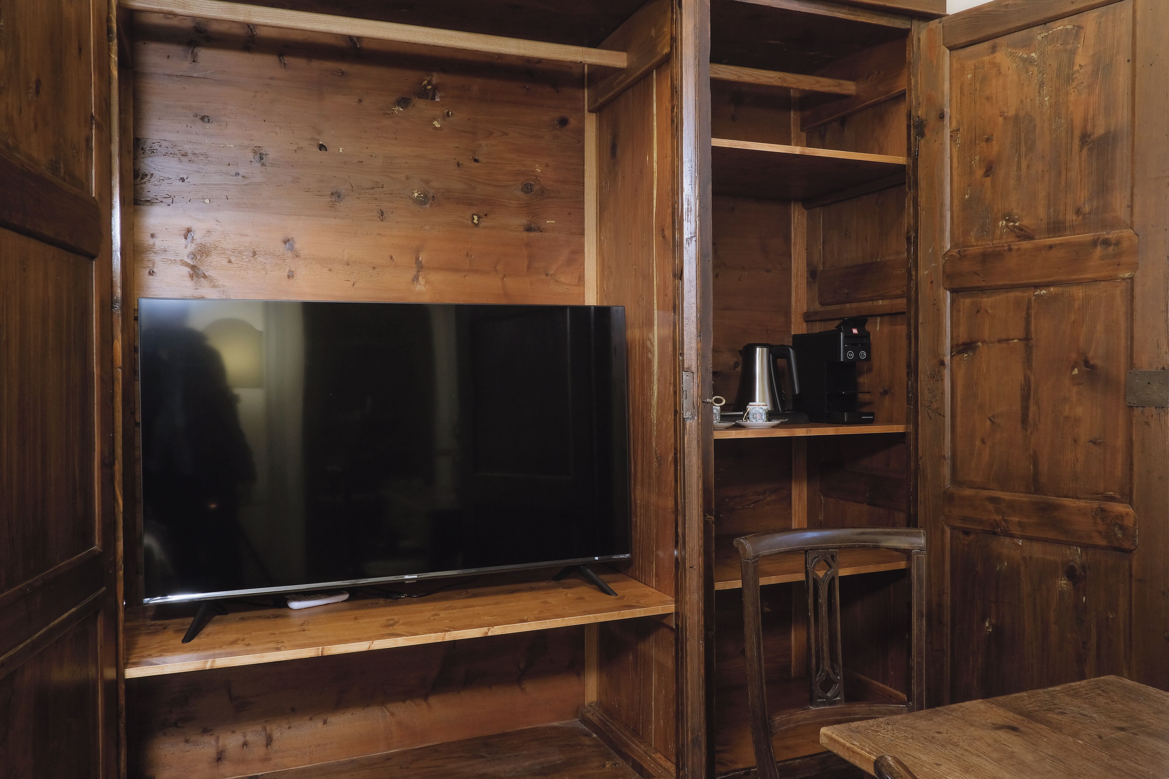 Un intérieur en bois avec une télévision posée sur une étagère, une chaise et une table.