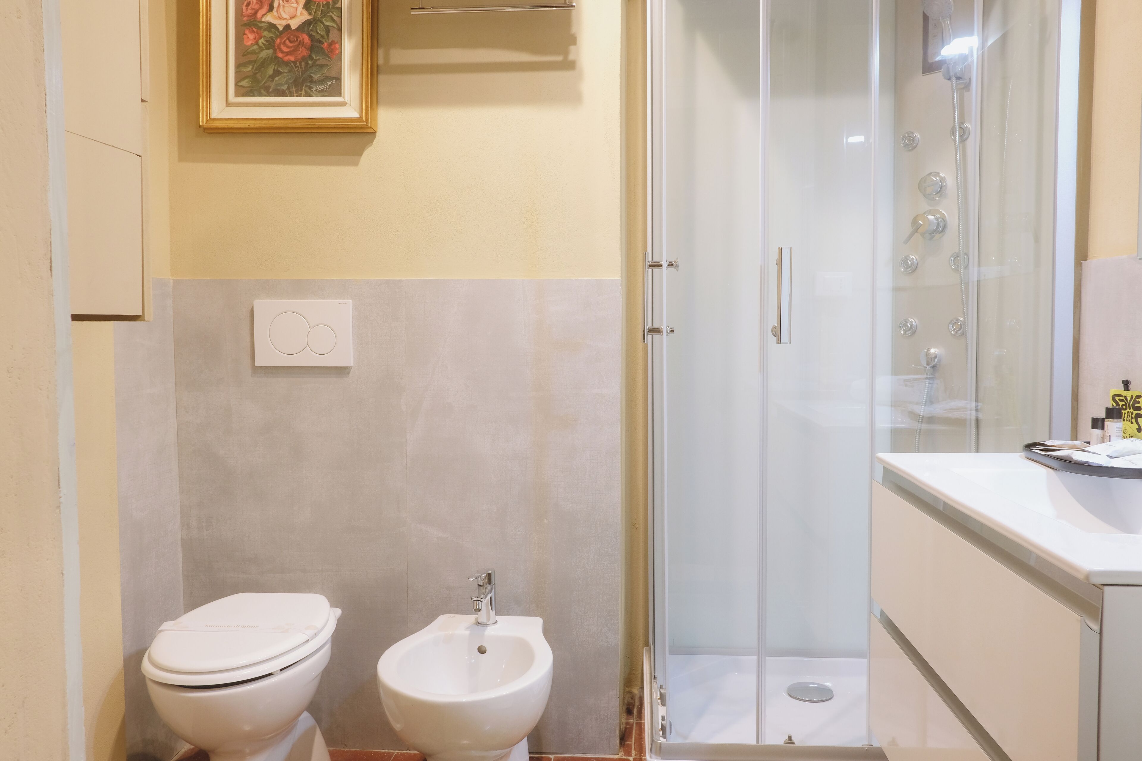 A bathroom with a toilet, bidet, and a glass-enclosed shower.