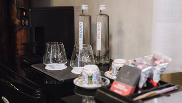 A coffee station with a coffee machine, two glass bottles labeled 'RECOARO', and several cups and saucers.