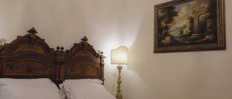 A bed with a wooden headboard, a bedside lamp, and a framed painting on the wall.