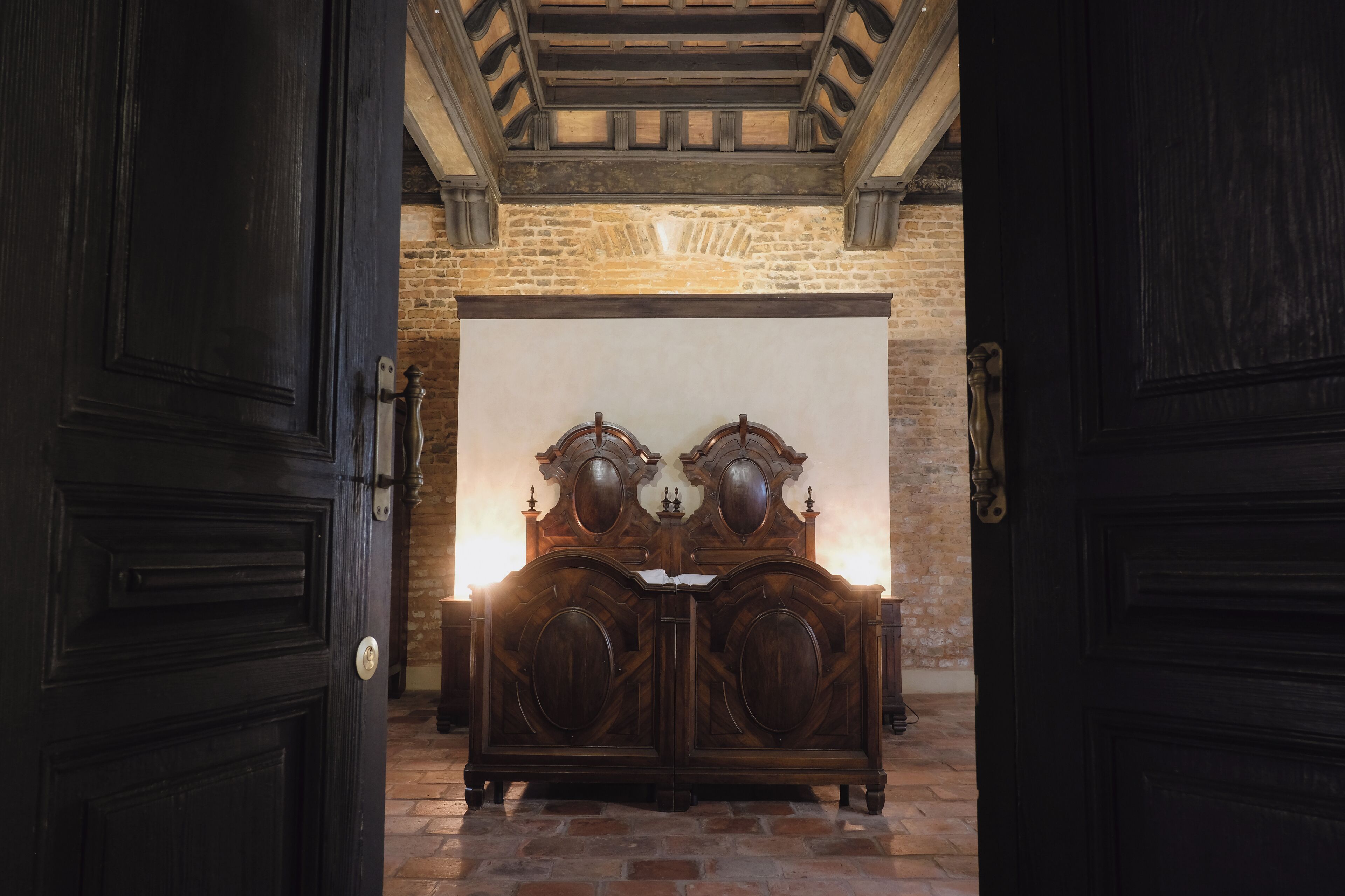 A room with a large wooden bed, a stone wall, and a wooden ceiling.