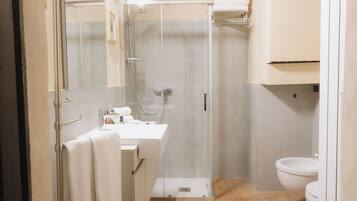 Un baño moderno con ducha de vidrio, un lavamanos blanco y un inodoro.
