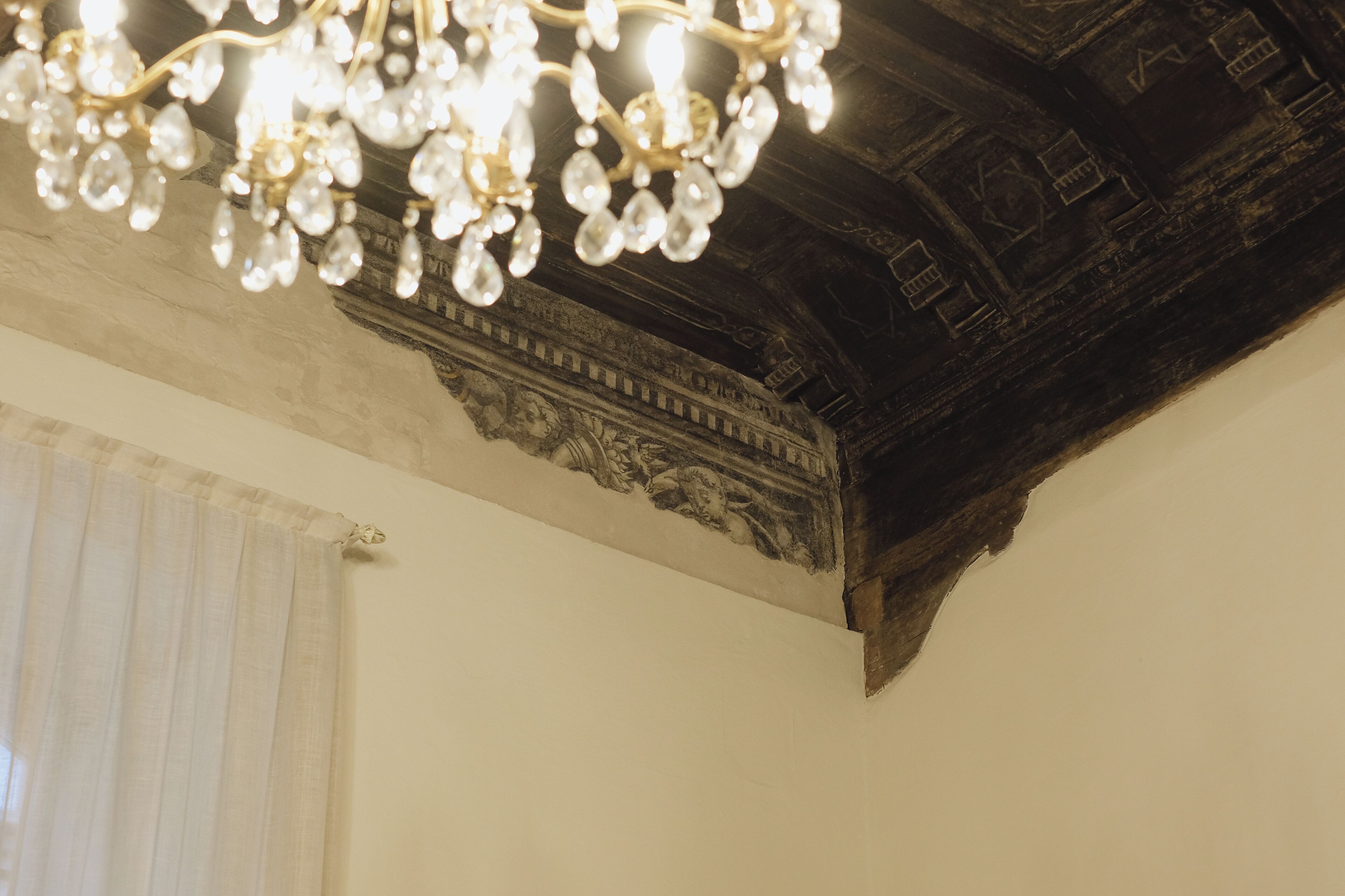 Un lustre orné de douilles en verre transparent, suspendu à un plafond en bois foncé.
