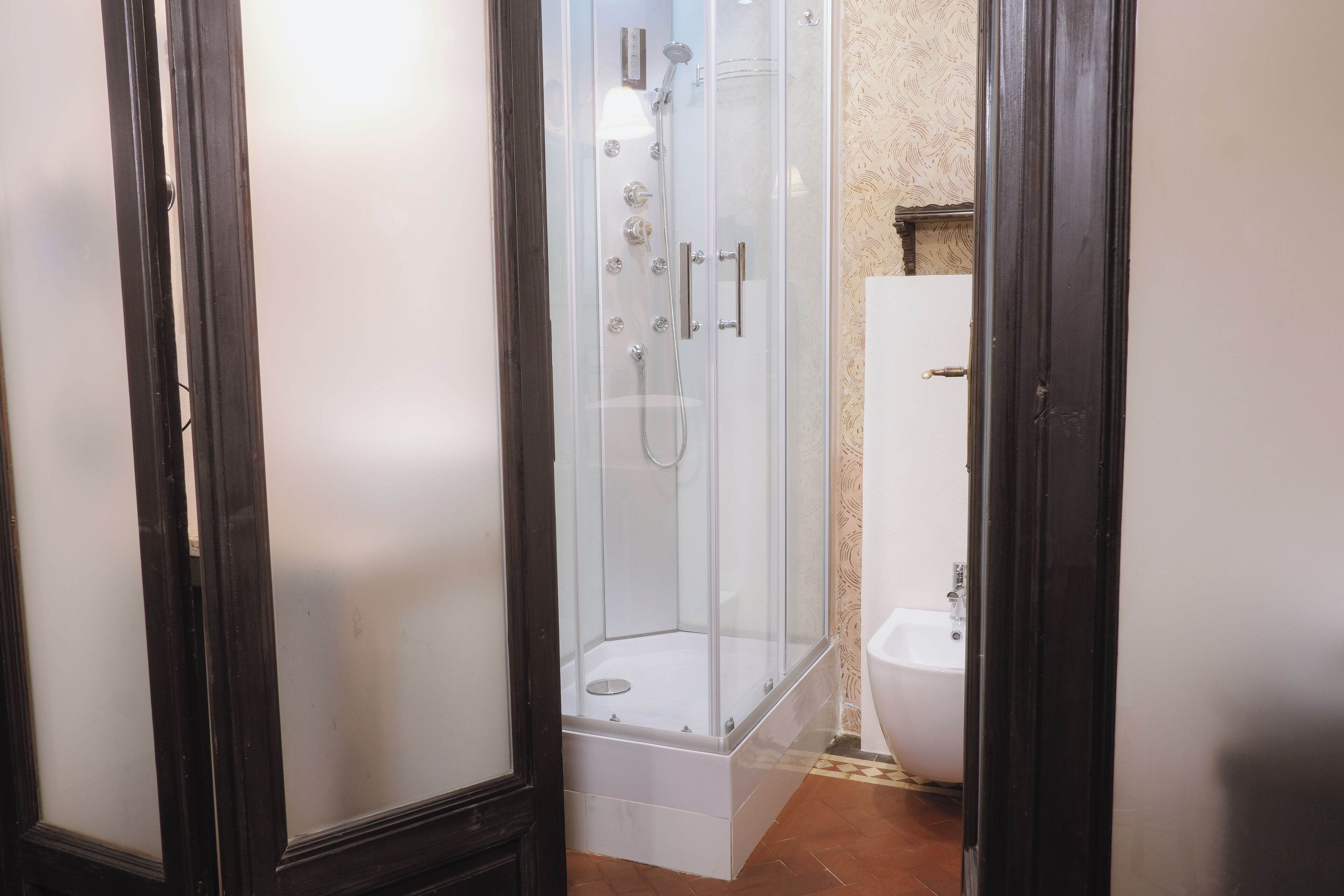 Eine Duschkabine mit Glas, eine weiße Badewanne und ein Bidet in einem Badezimmer.