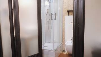 Eine Duschkabine mit Glas, eine weiße Badewanne und ein Bidet in einem Badezimmer.