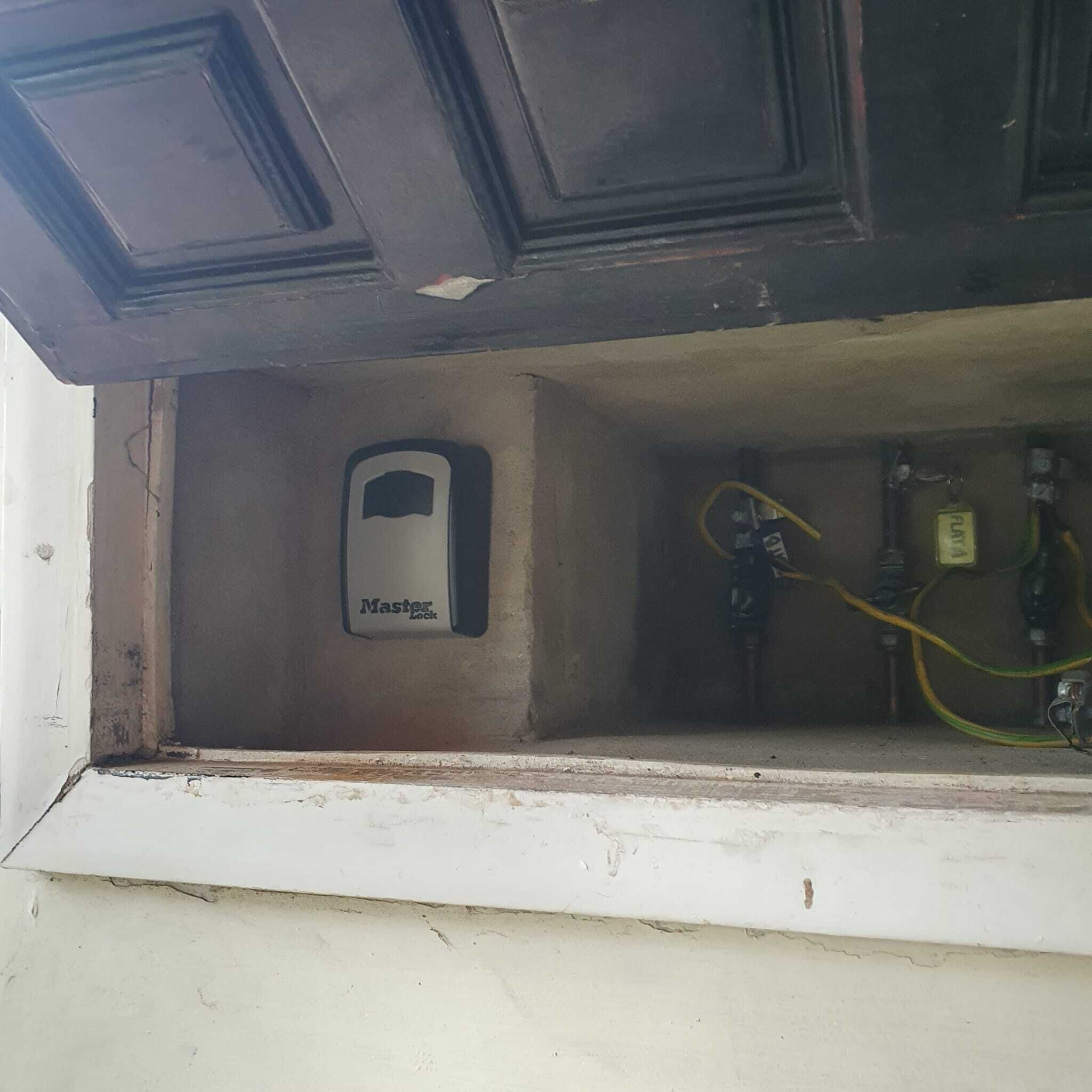 A utility room with a Master Lock device, electrical panels, and exposed wiring.