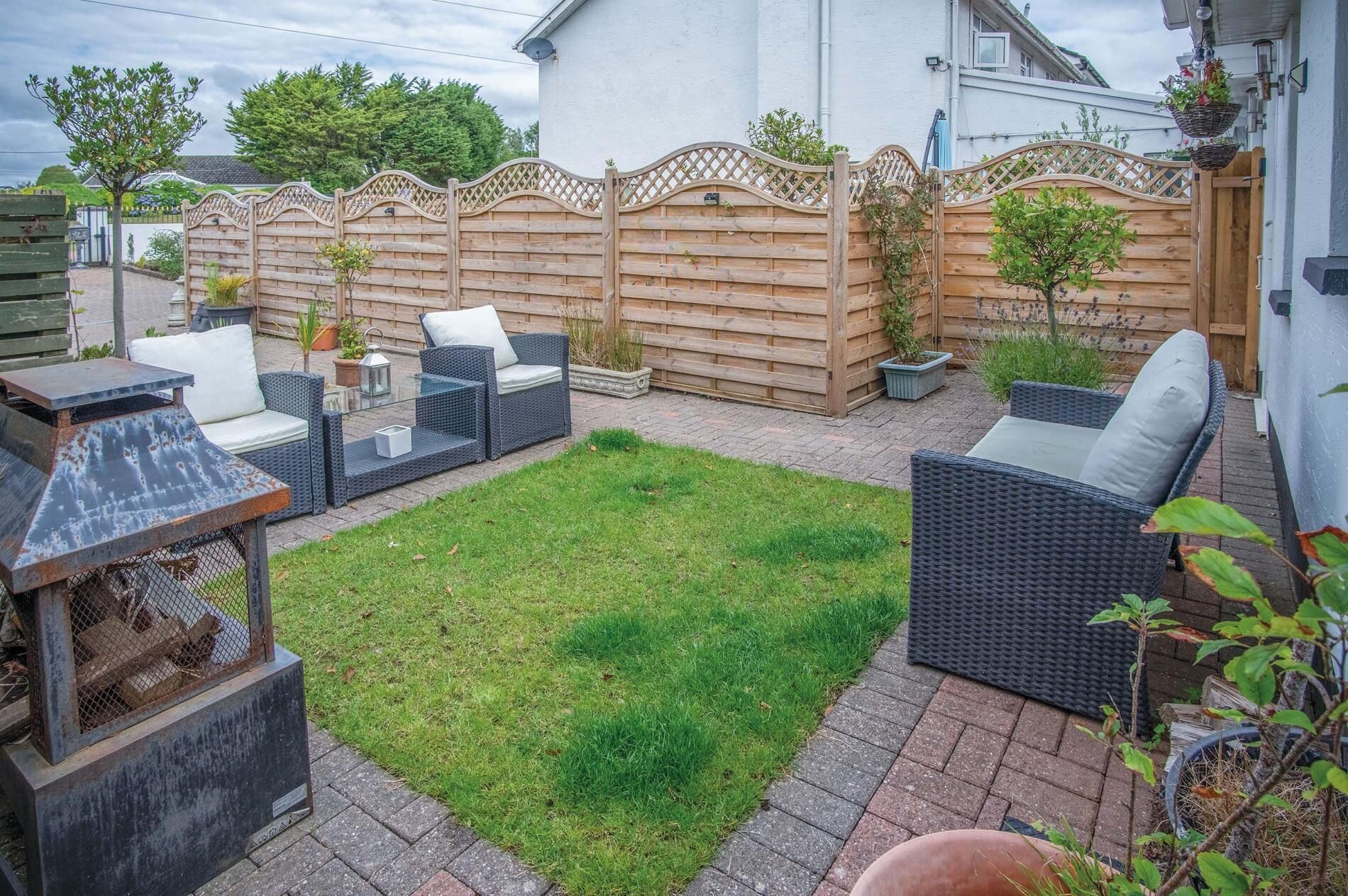 A patio area with outdoor furniture, a grill, and a wooden fence.