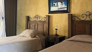 Ein Zimmer mit zwei Betten, einem Nachttisch mit Lampe, einem gerahmten Bild an der Wand und einer Holzbodenverkleidung.