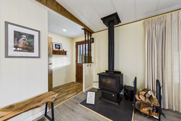 A cozy room with a wooden bench, a black wood-burning stove, and a framed picture on the wall.