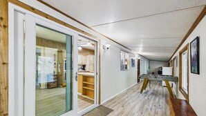 A hallway with a wooden floor, a sliding glass door leading to a kitchen, and a bench along the wall. - Explore Redwood National Park with Hot Tub, Wood Stove, and Fire Pit! (Orick)