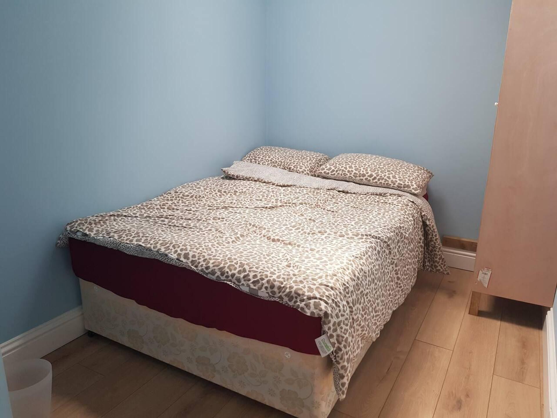 Un dormitorio con cama, mesita de noche y suelo de madera.