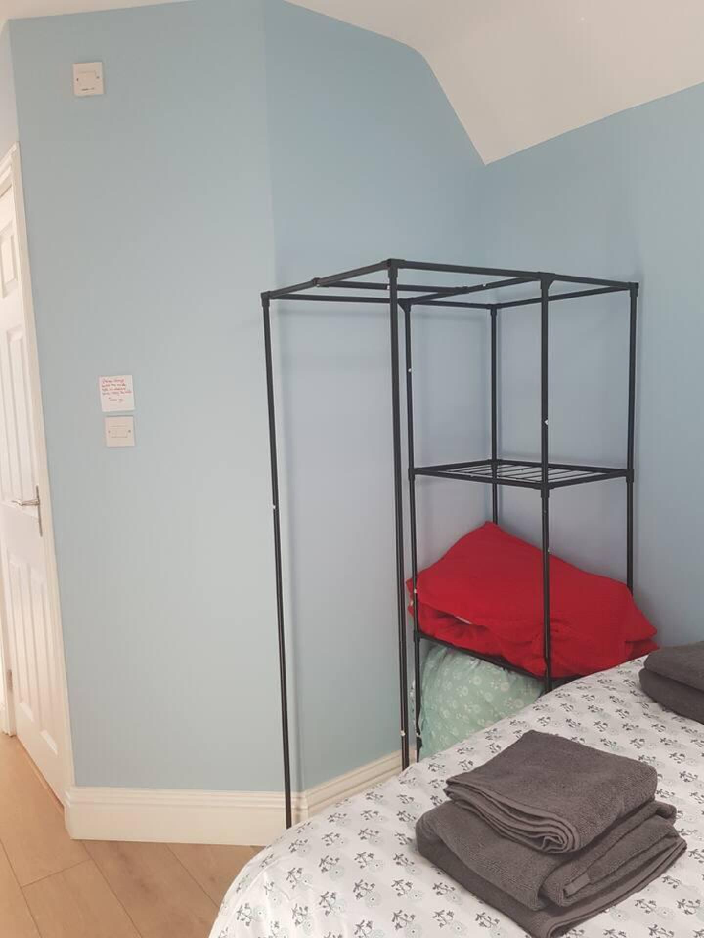Une pièce comprenant un lit, un meuble de rangement en métal et une porte.