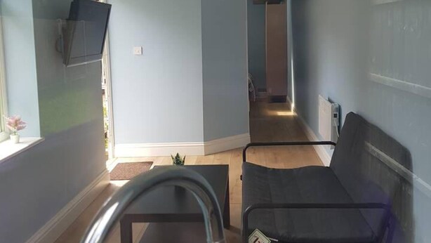 A compact living space with a kitchenette, a small seating area, and a view of the outdoors. - Cozy Studio in Luton (Luton)