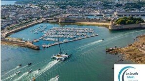 Un port de plaisance où sont amarrés des bateaux, entouré d’une vue sur la ville et bordé par une vaste étendue d’eau.
