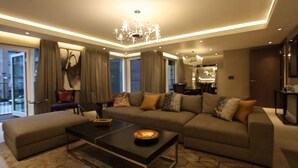 A modern living room with a sectional sofa, a coffee table, and a chandelier. - Luxurious Three Bedroom Flat in Chelsea Creek (London)