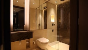 A modern bathroom with a marble vanity, a toilet, and a glass shower enclosure. - Luxurious Three Bedroom Flat in Chelsea Creek (London)