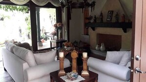 Un salon avec deux canapés blancs, une table basse en bois ornée de bougies, un lustre et une cheminée.