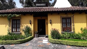 Un bâtiment jaune avec un toit en tuiles, un dôme blanc et un chemin de pierre menant à l’entrée.