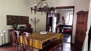 Un coin repas avec une table et des chaises en bois, un lustre et une vue sur la cuisine.
