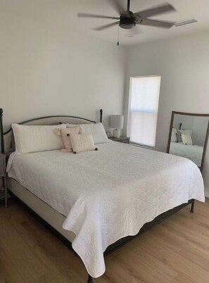 Restful retreat with a large bed, ceiling fan, and nightstand with lamp.