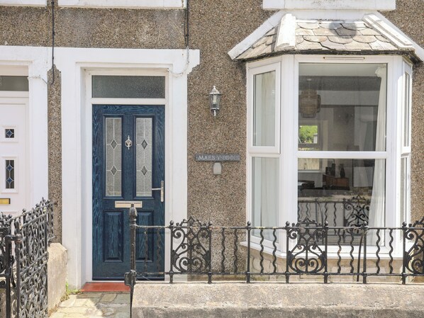 A townhouse with a blue front door, a bay window, and a stone facade.