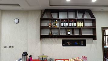 A buffet setup with a red tablecloth, a variety of beverages, and food items.