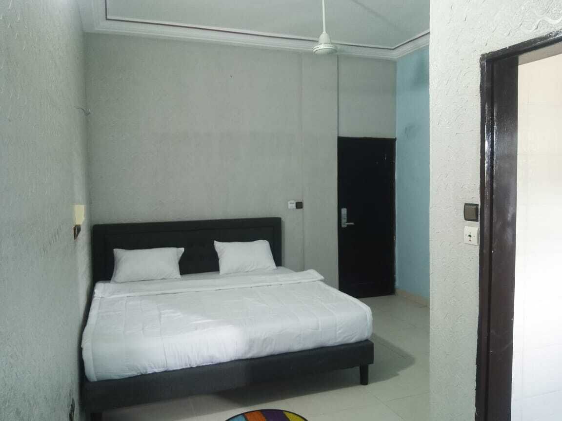 A bedroom with a bed, a ceiling fan, and a door.