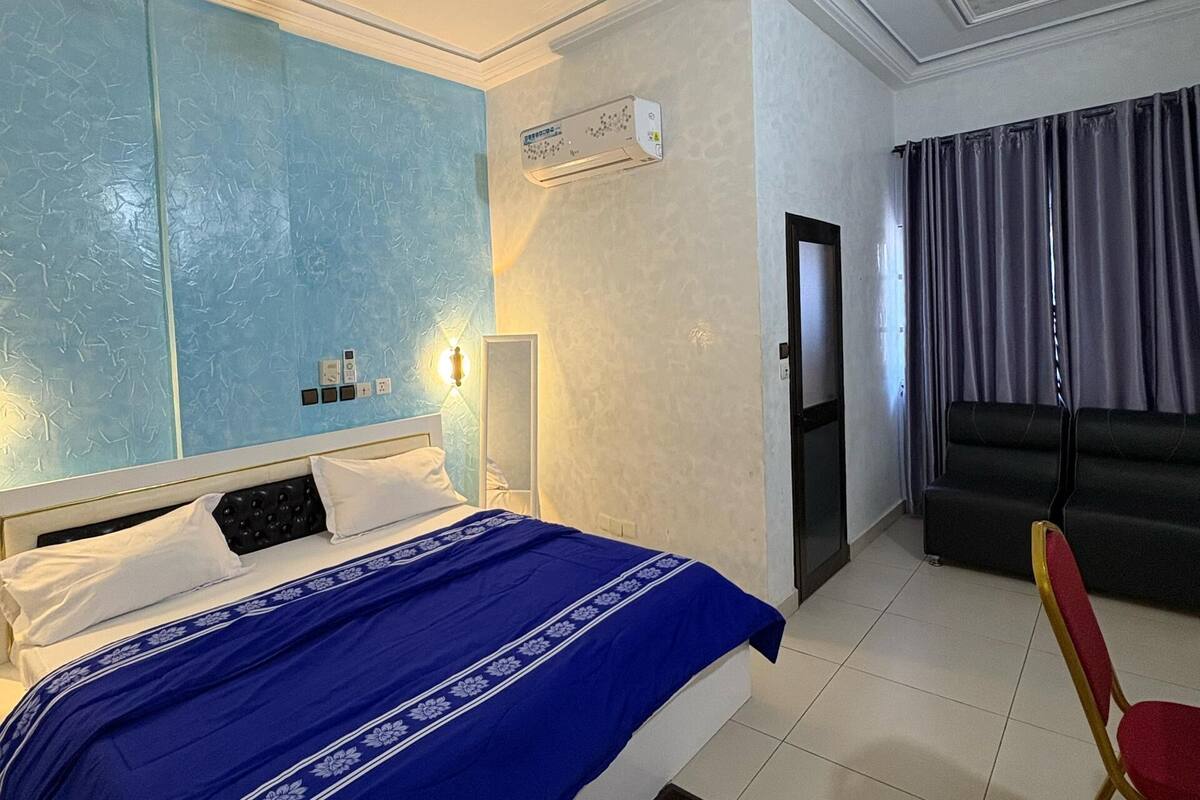 Une chambre d’hôtel équipée d’un lit, d’un ventilateur de plafond, d’un climatiseur, d’un canapé et d’un fauteuil.