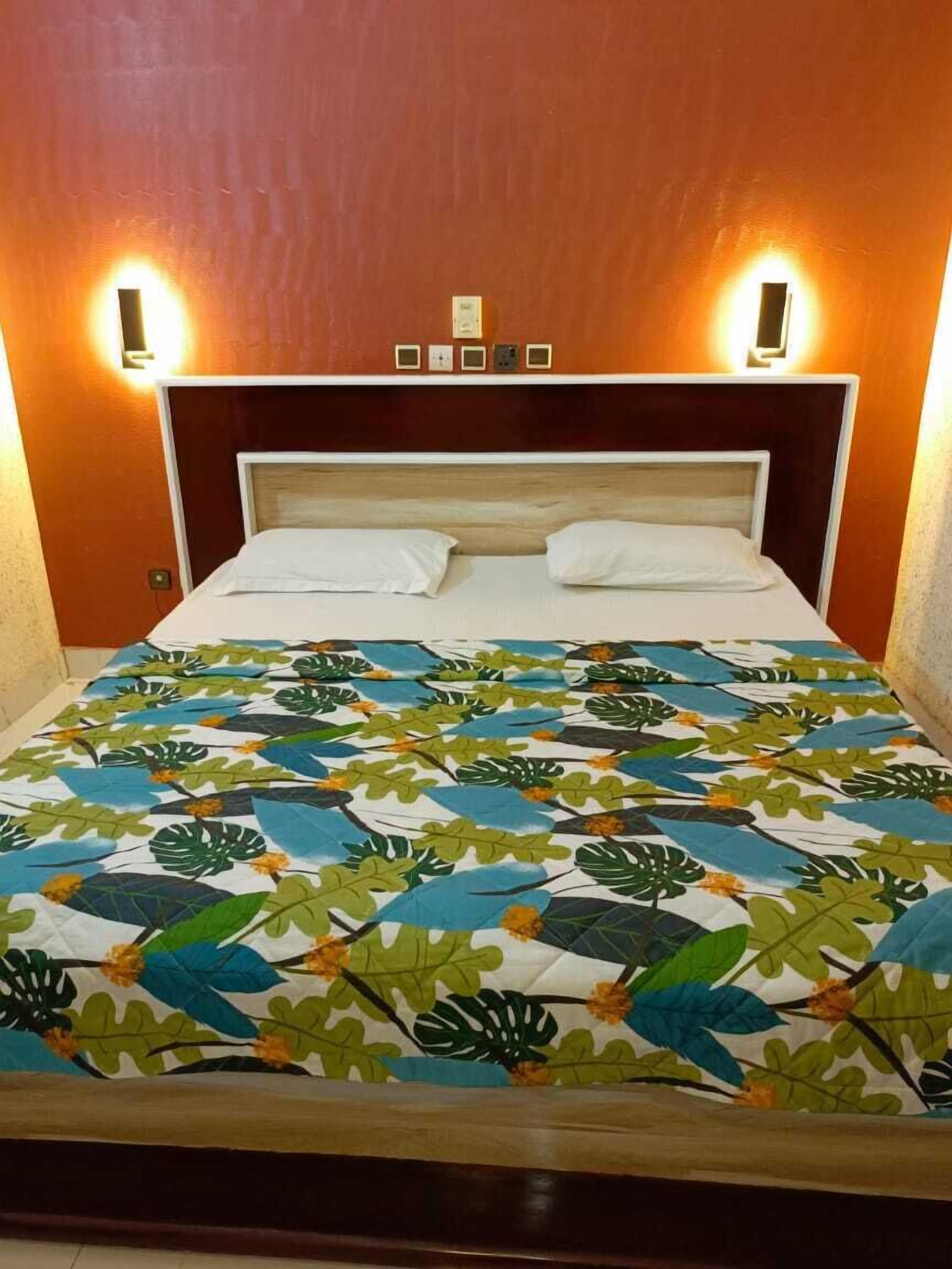 A bed with a floral-patterned bedspread, two bedside lamps, and a wooden headboard.