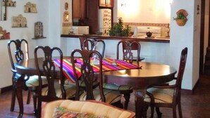 A dining area with a round table, six chairs, and a colorful table runner. - Casita Las Tradiciones (Antigua Guatemala)