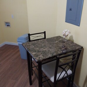 A cozy dining area with a square table and four chairs, complemented by a vase with fresh flowers.