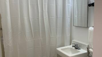 Ein Badezimmer mit Duschvorhang, Waschbecken, Spiegel und Toilette.