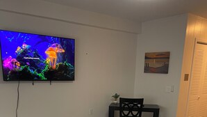 Un dormitorio con una cama grande, un televisor en la pared, una mesita pequeña y una silla.