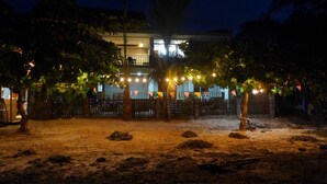 A building with a fenced courtyard, trees, and string lights.