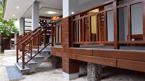 A staircase with wooden railings leading to a covered area with a door and windows.