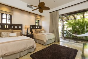 Two large beds with wooden headboards and matching bedding, a hammock, and a ceiling fan.