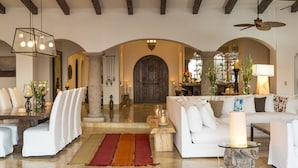 A spacious living area with a large arched doorway, white sofas, a coffee table, and a chandelier.
