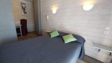 A modern hotel room with a large bed, a desk, and a chair.
