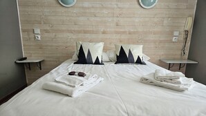 Una cama bien hecha con sábanas blancas, dos almohadas y un par de gafas de sol sobre la cama.