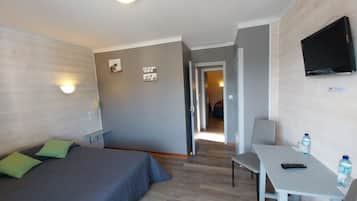 Habitación de hotel con cama, escritorio, silla, televisión y botella de agua.