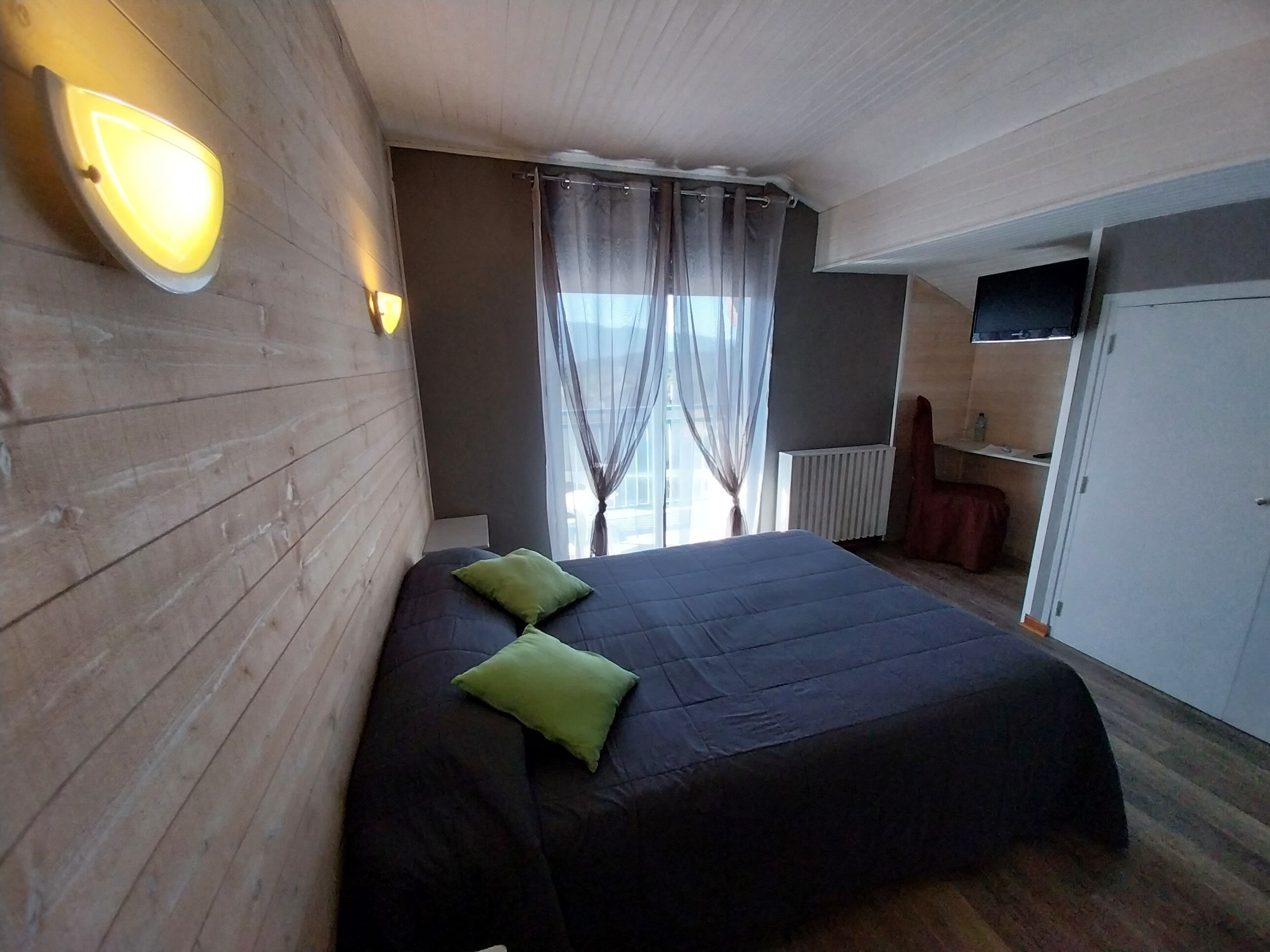 A bedroom with a large bed, a wardrobe, a radiator, and a TV.